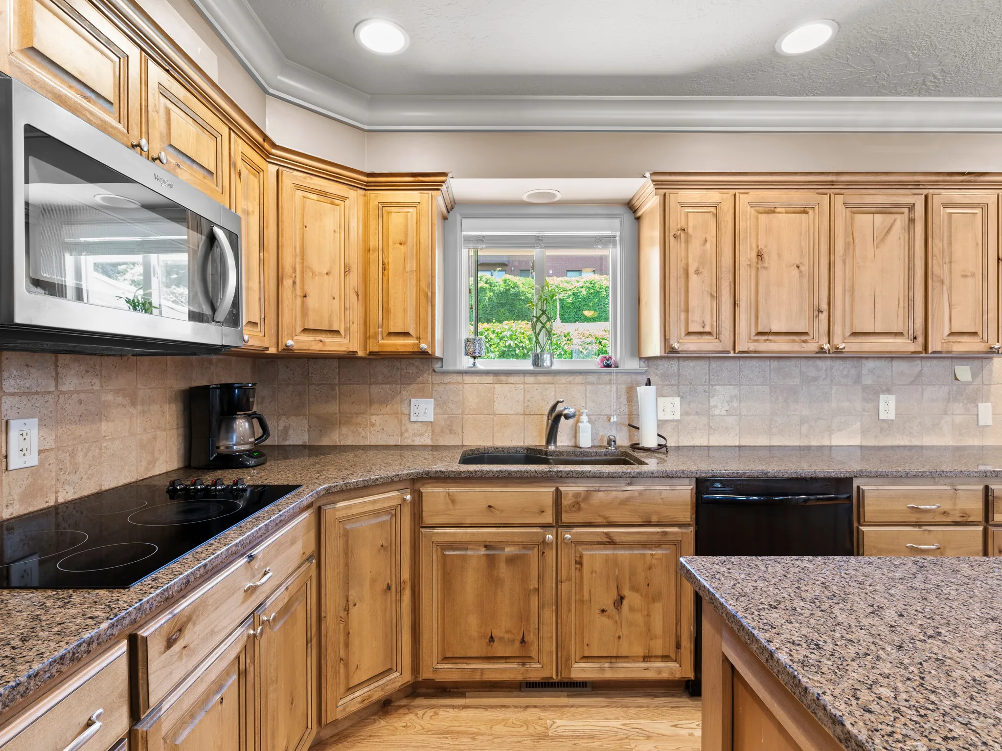 Kitchen featuring black appliances, dark stone counters, decorative backsplash, and crown molding