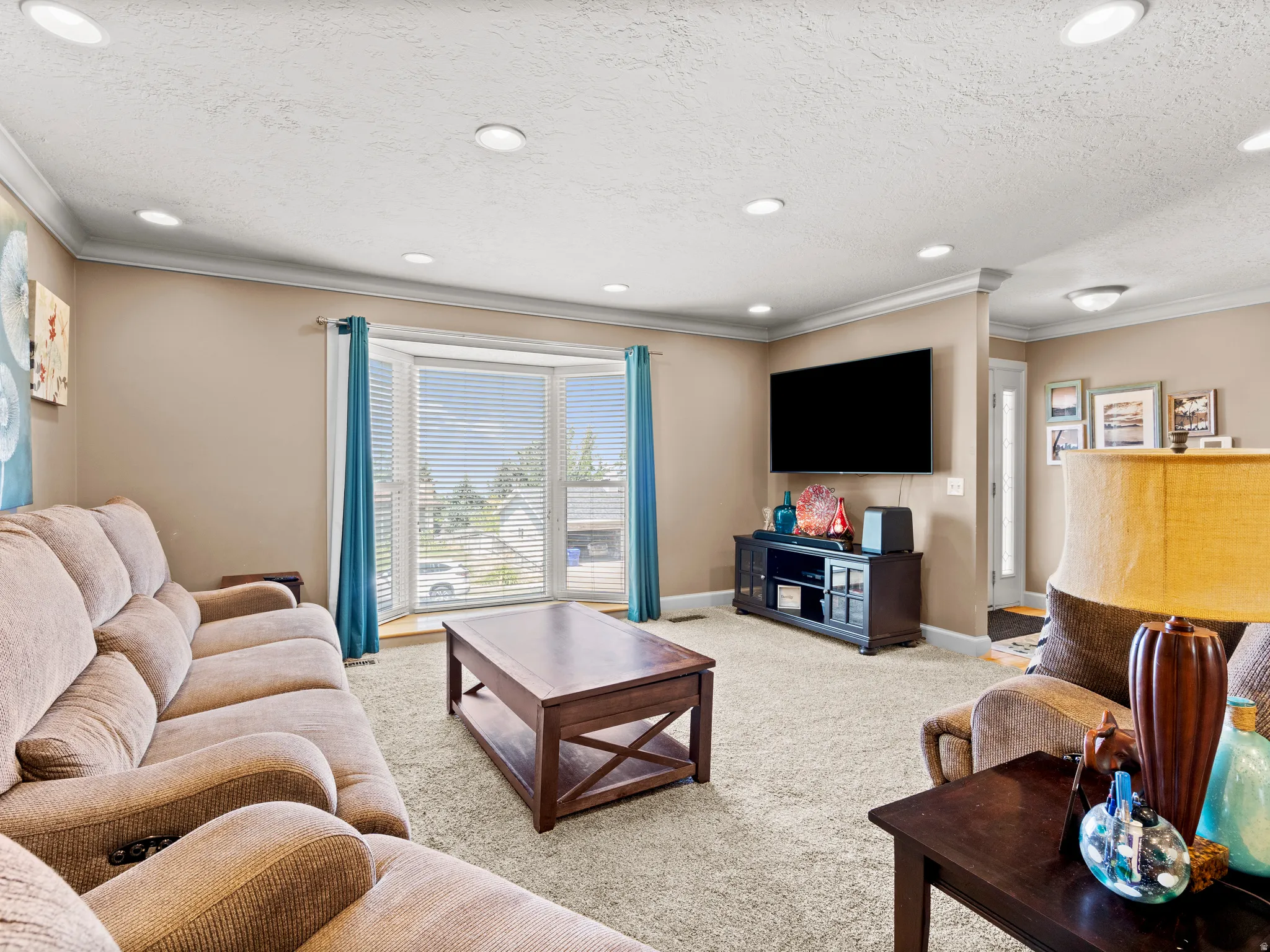Living room featuring light carpet, ornamental molding, recessed lighting, and a textured ceiling