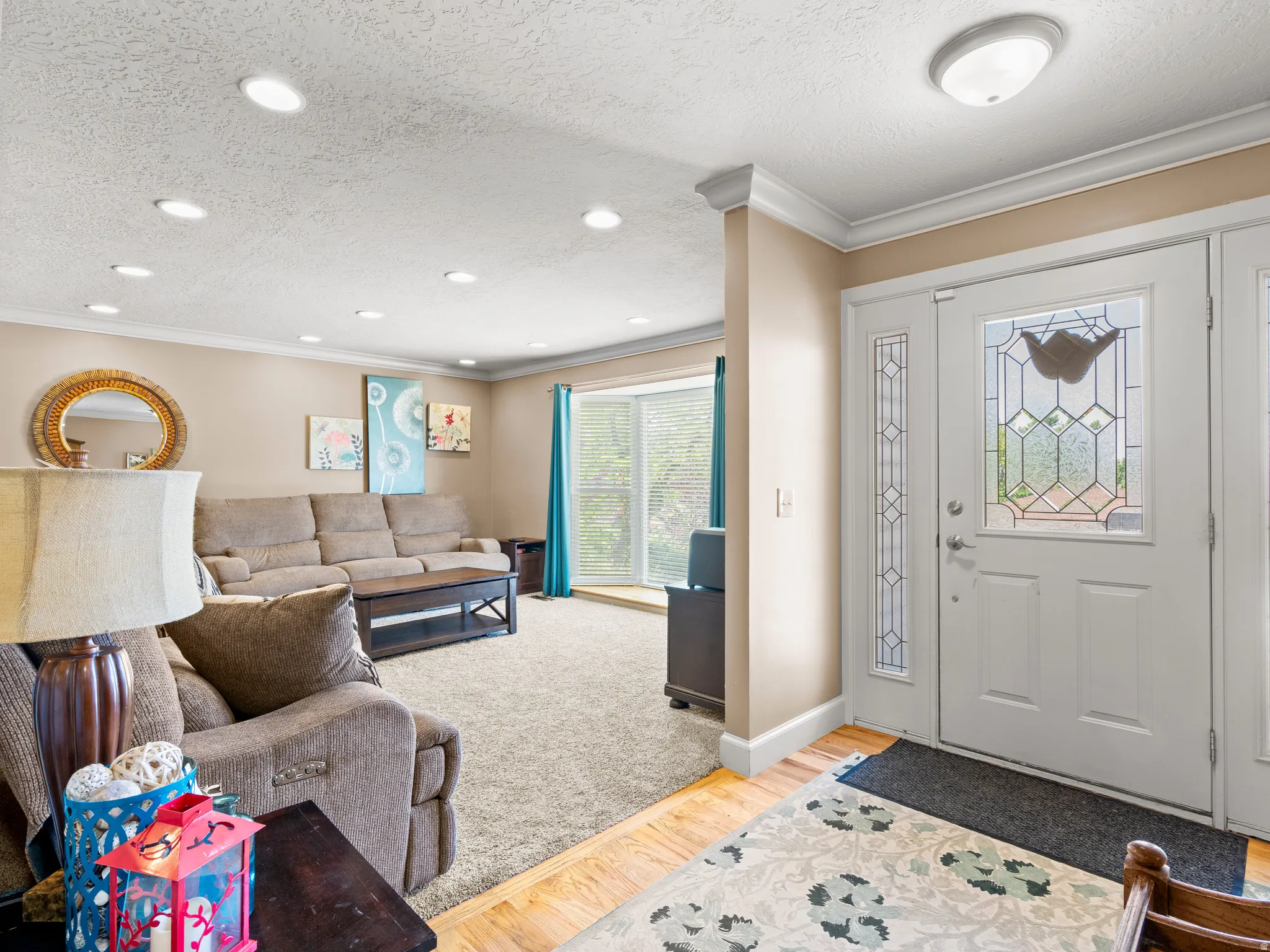 Foyer entrance featuring light wood-style floors, ornamental molding, and a textured ceiling