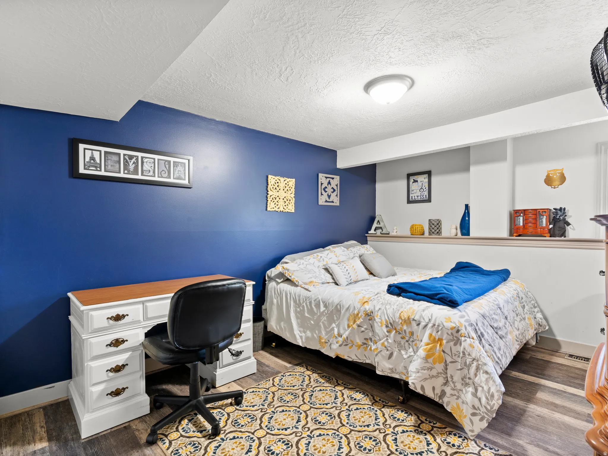 Bedroom with a textured ceiling, dark wood-style flooring, and a desk