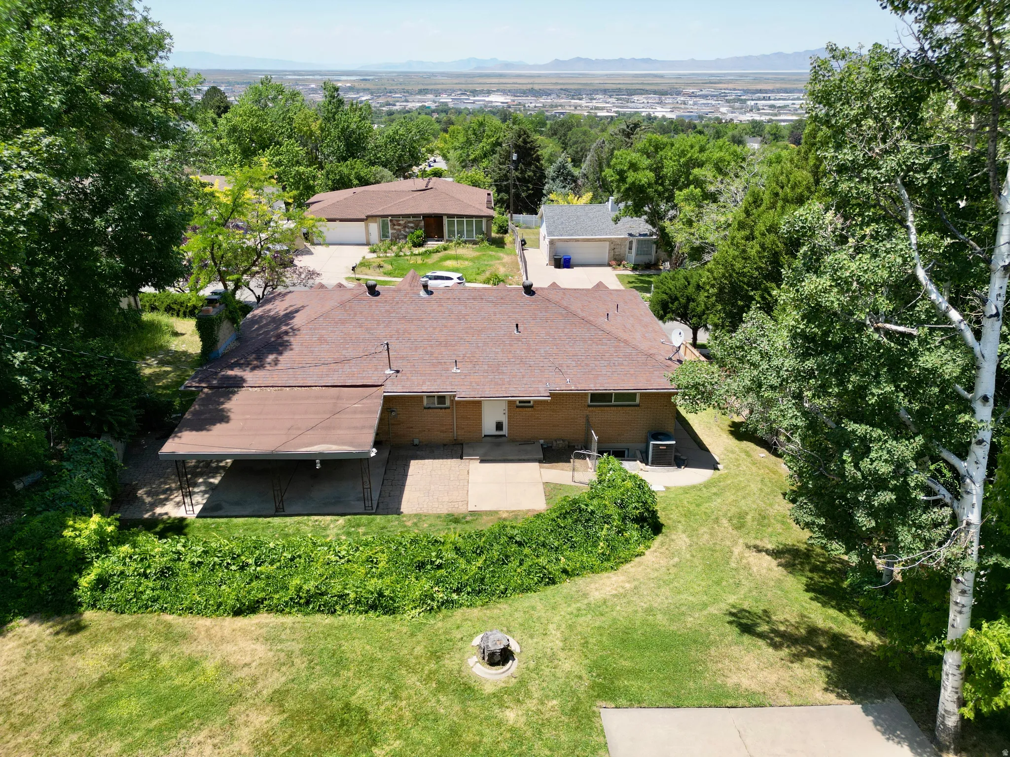Aerial view of property and surrounding area featuring a mountainous background and a tree filled landscape