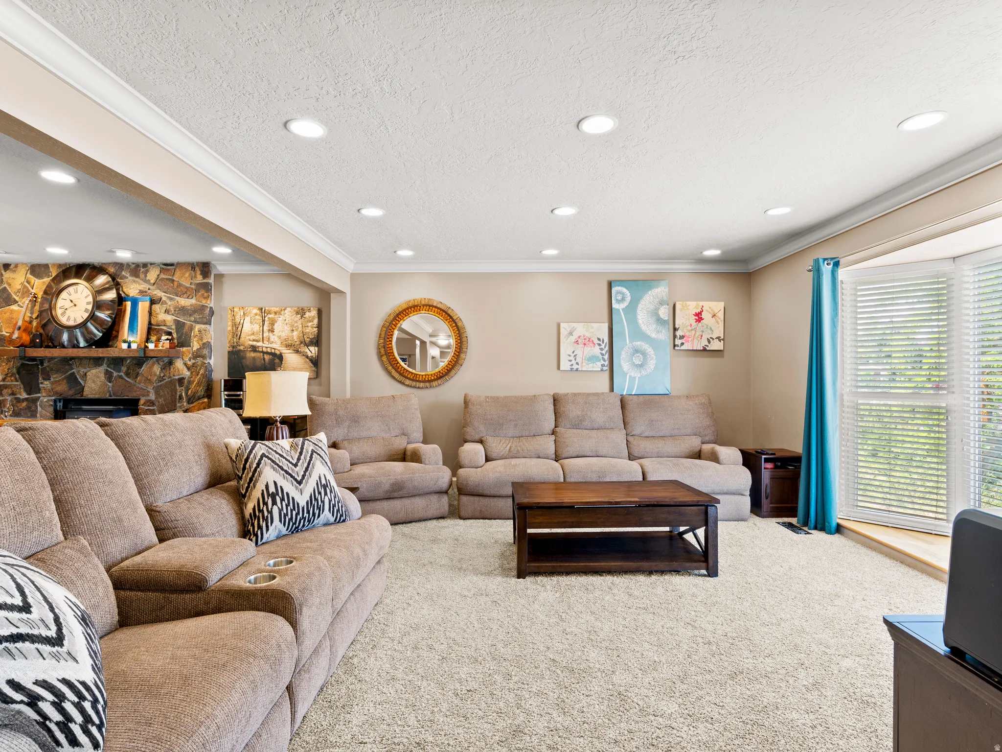 Living room with a fireplace, a textured ceiling, carpet flooring, crown molding, and recessed lighting