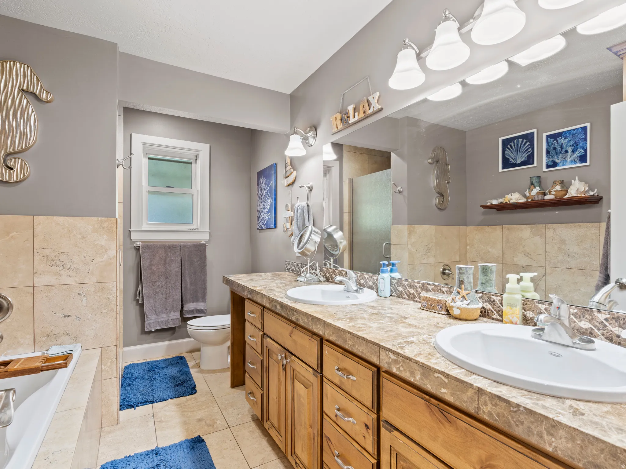 Full bathroom featuring a bath, double vanity, light tile patterned floors, and a walk in shower