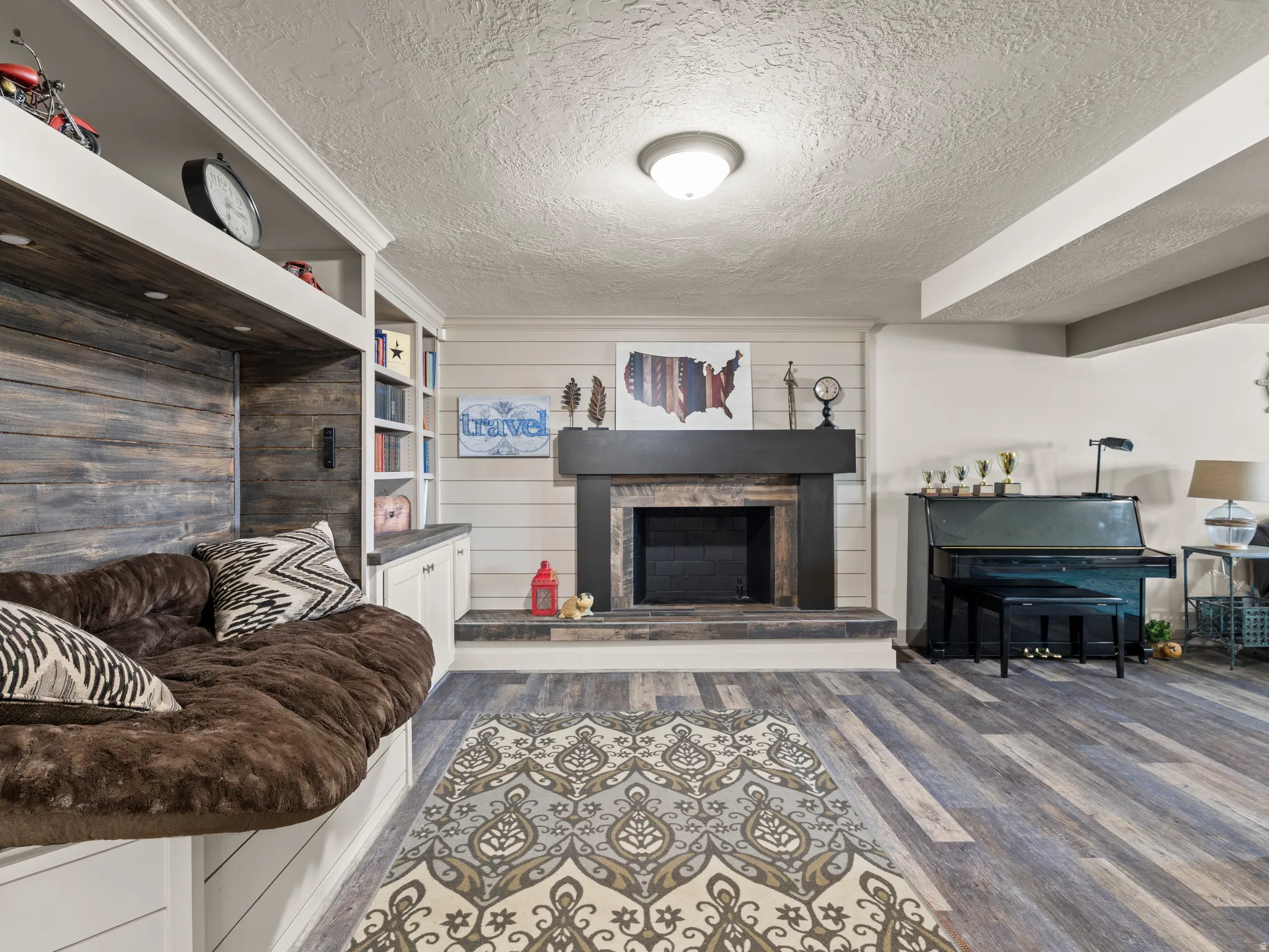 Living room with dark wood-type flooring, a textured ceiling, and a fireplace with raised hearth