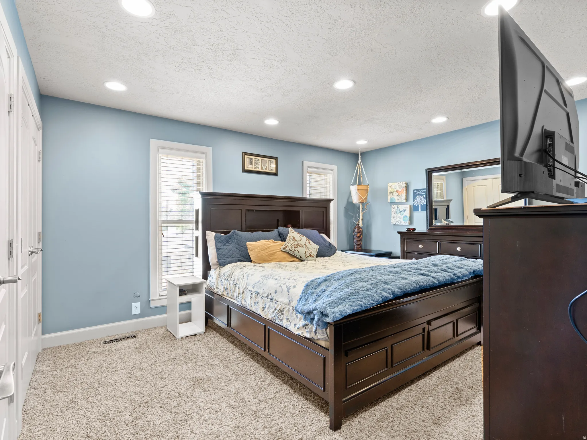 Bedroom with light colored carpet, a textured ceiling, and recessed lighting