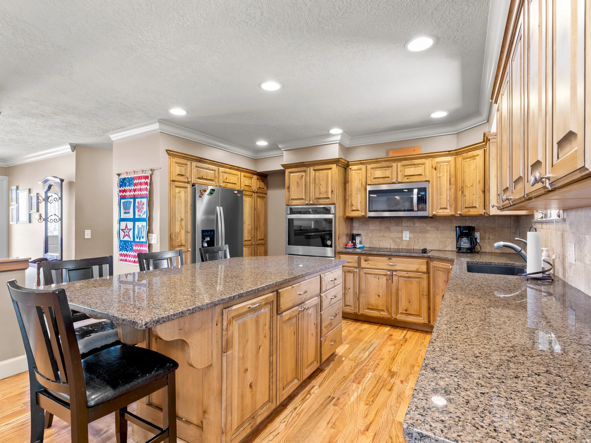 Kitchen featuring light wood-style floors, dark stone counters, stainless steel appliances, backsplash, and a center island