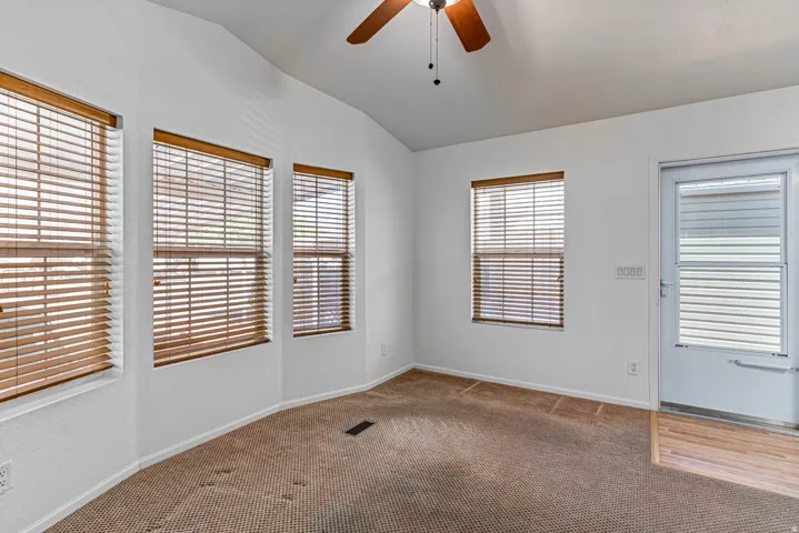 Living room with ceiling fan, vaulted ceiling, and carpet