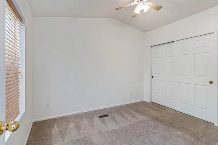 Primary bedroom featuring carpet floors, lofted ceiling, ceiling fan, and a closet