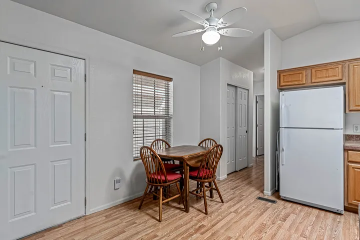 Dining area with a ceiling fan, vaulted ceiling, and light wood-type flooring