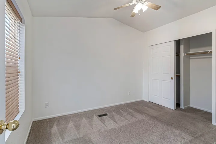Primary bedroom with carpet floors, a ceiling fan, lofted ceiling, and a closet
