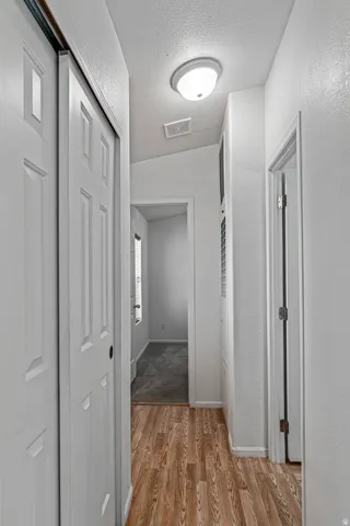 Corridor featuring a textured ceiling and light wood-style flooring