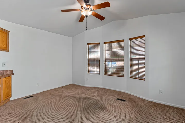 Living room with a ceiling fan, carpet, and vaulted ceiling