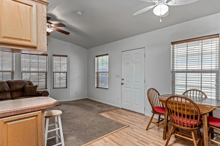 Dining space featuring ceiling fan, lofted ceiling, dark wood-style floors, and plenty of natural light