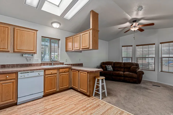 Kitchen featuring a peninsula, open floor plan, dishwasher, a kitchen breakfast bar, and light wood finished floors