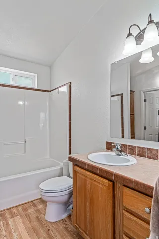 Full bathroom featuring vanity, light wood finished floors, bathtub / shower combination, and a textured wall