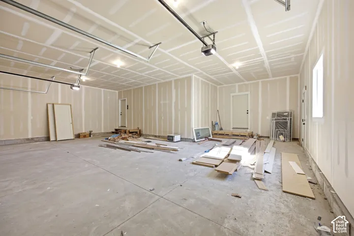 Spacious garage featuring concrete flooring and unpainted drywall