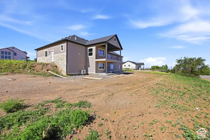 Newly constructed residence featuring a two-story exterior with stucco and stone accents, dual balconies, and a dark shingle roof