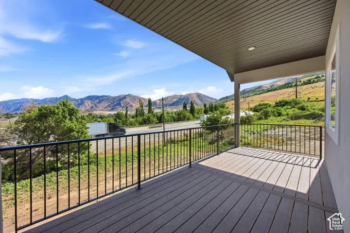 Covered outdoor deck featuring composite decking, black metal railings, a recessed ceiling light, and white window trim