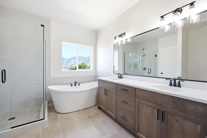 Modern bathroom featuring a freestanding soaking tub, a separate glass-enclosed shower with tile surround, and a dual vanity with a large mirror
