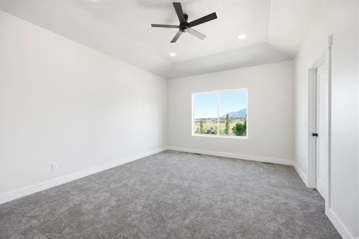 Carpeted room featuring a vaulted ceiling with a ceiling fan, recessed lighting, and a large window