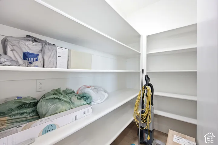 Expansive pantry featuring multi-level shelving, bright white finishes, and a conveniently placed electrical outlet