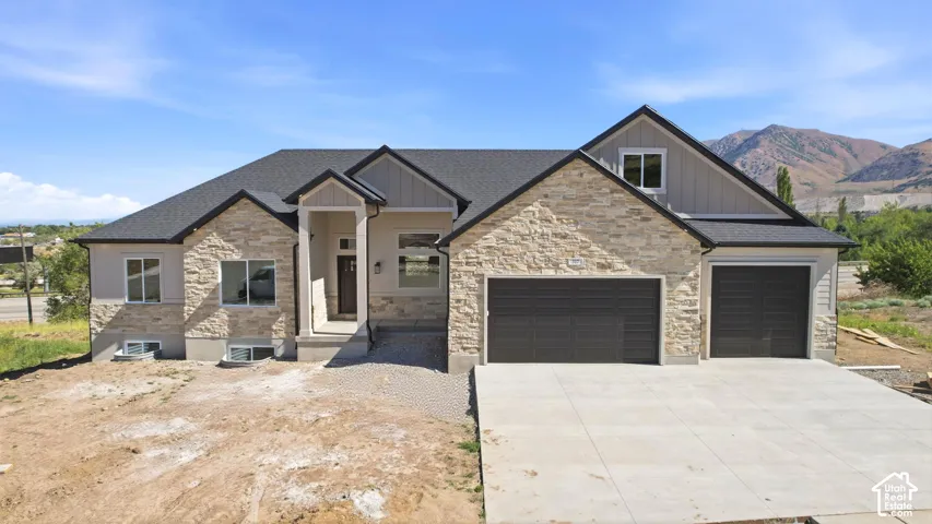 Contemporary residence featuring stone and siding exterior, dark shingles, an attached multi-car garage, and a concrete driveway