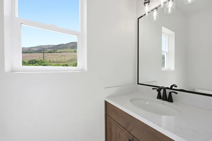Bathroom vanity featuring a wood-finish cabinet, white countertop, and integrated sink with a matte black faucet