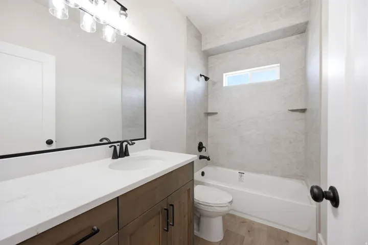 Bathroom featuring a wood-finish vanity with a white countertop, an undermount sink, and matte black fixtures
