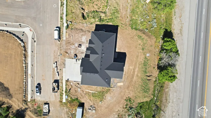 Newly constructed residence featuring a dark shingle roof and a concrete driveway