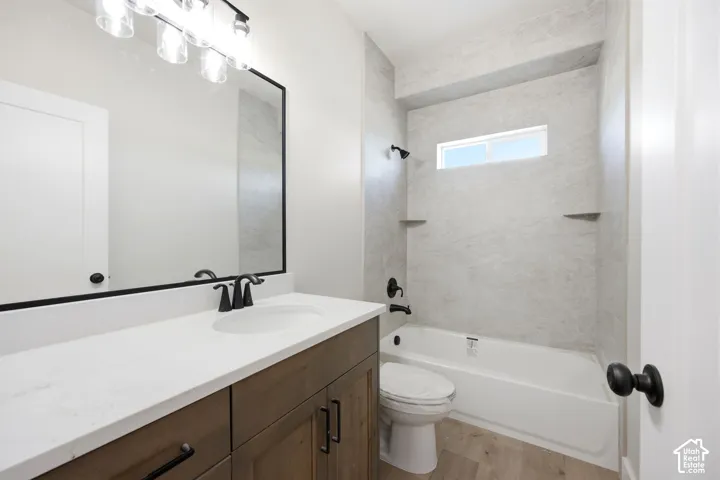 Bathroom featuring a wood-finish vanity with a white countertop, an undermount sink, and matte black fixtures