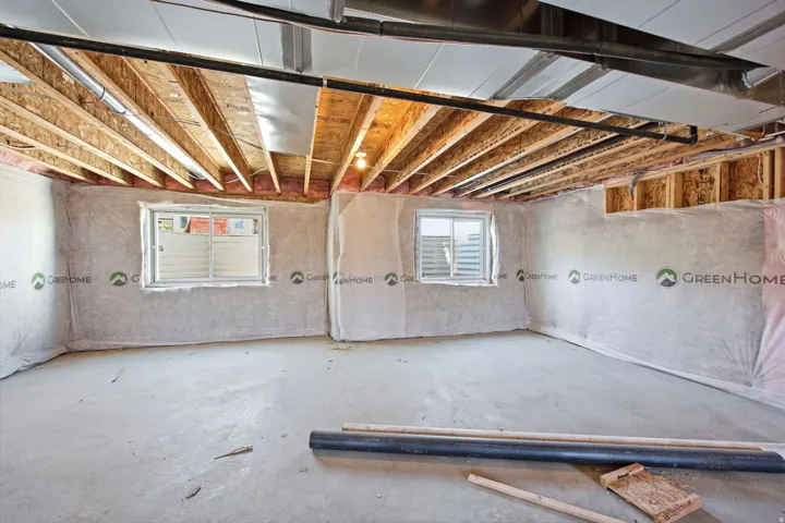Unfinished basement with exposed wood joists and concrete flooring, featuring two windows with white grilles