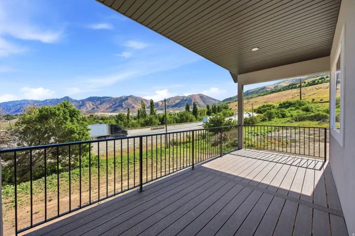 Covered outdoor deck featuring composite decking, black metal railings, a recessed ceiling light, and white window trim