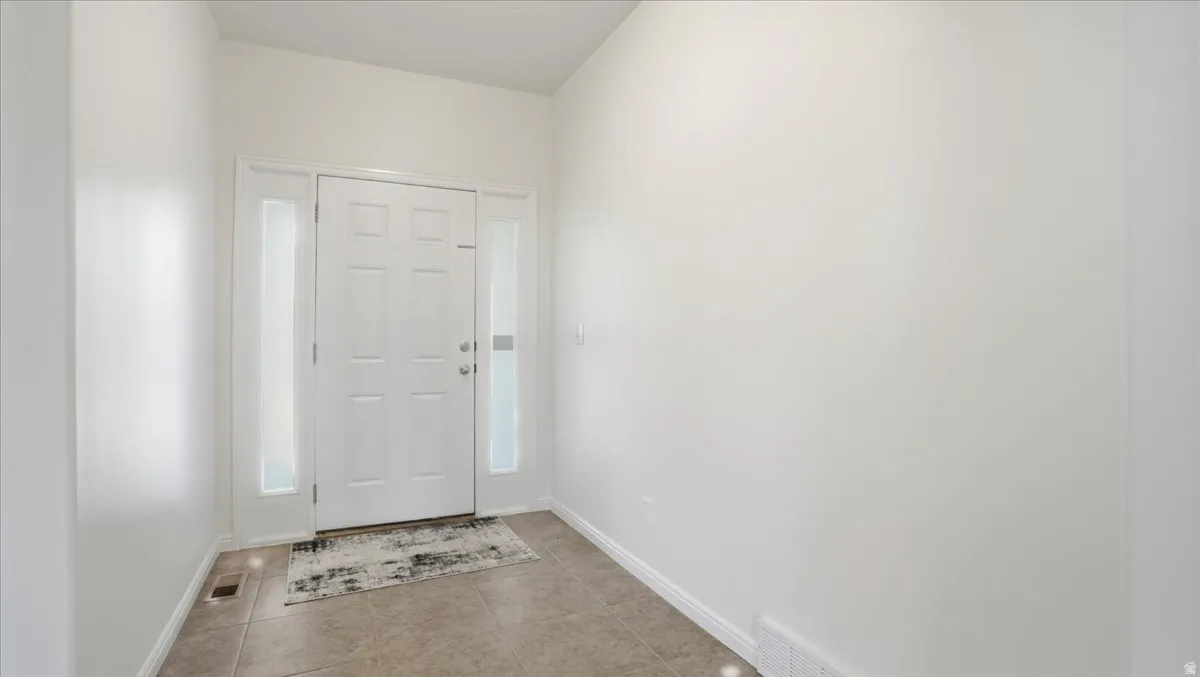 Foyer featuring a paneled entry door with sidelights, neutral wall tones, and tiled flooring