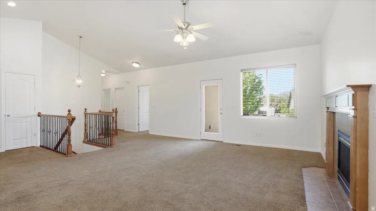 Spacious room featuring vaulted ceilings and neutral carpeting