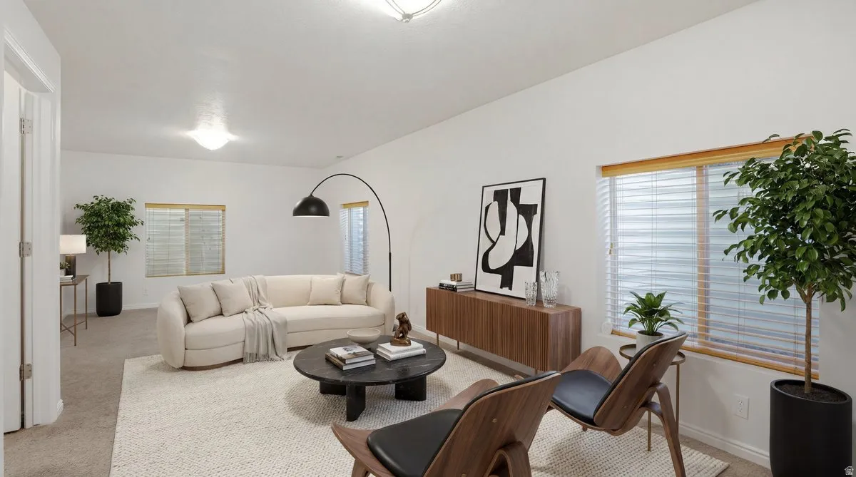 Bright living area featuring neutral carpeting, white walls, and recessed lighting