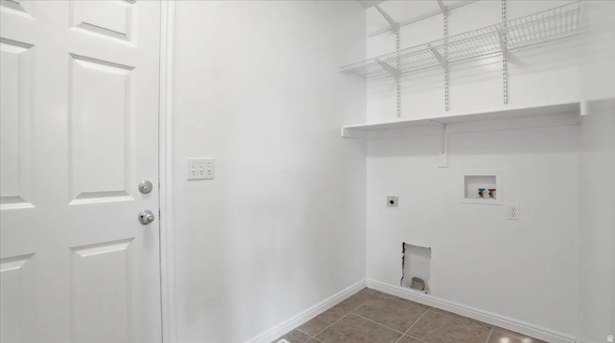 Laundry room with light tile patterned flooring, hookup for an electric dryer, and washer hookup