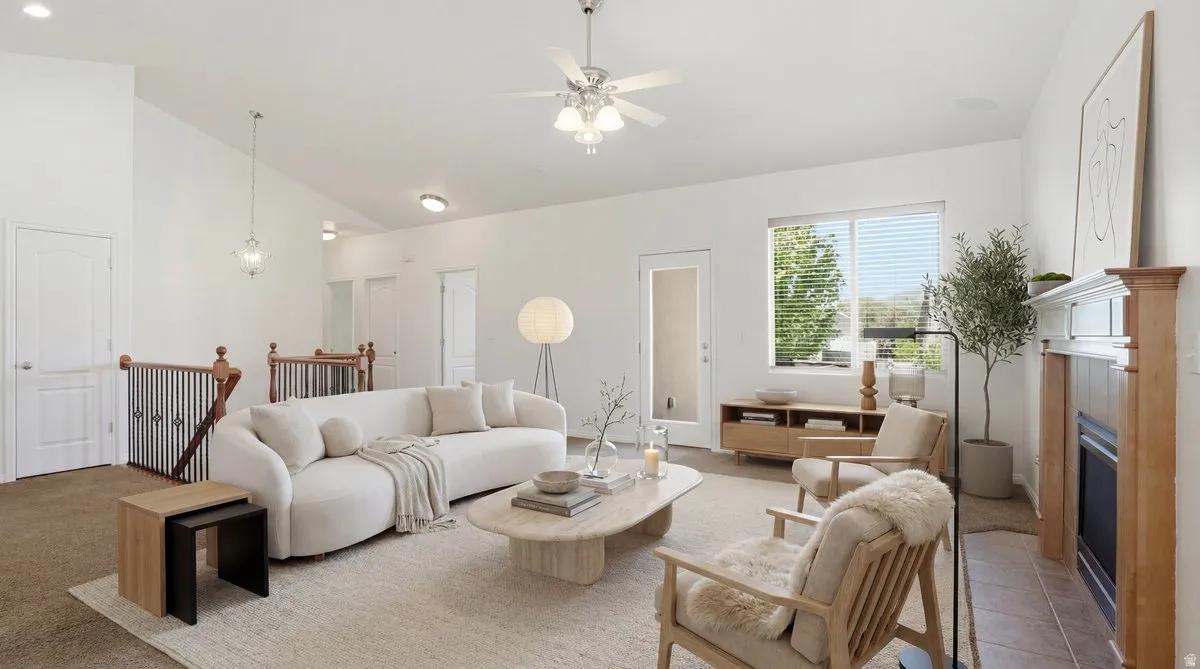 Spacious living area featuring vaulted ceilings, a ceiling fan with integrated lighting, and a prominent fireplace with a wood mantel