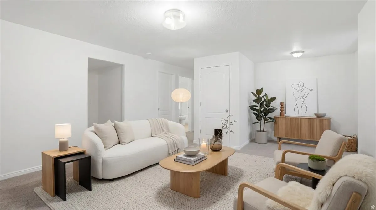 Living area with baseboards and light carpet
