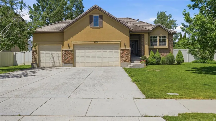 Stucco and stone facade home featuring a three-car garage and a concrete driveway
