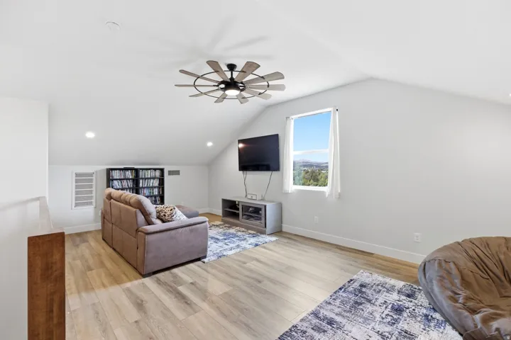 Living room featuring light wood-type flooring, ceiling fan, and recessed lighting