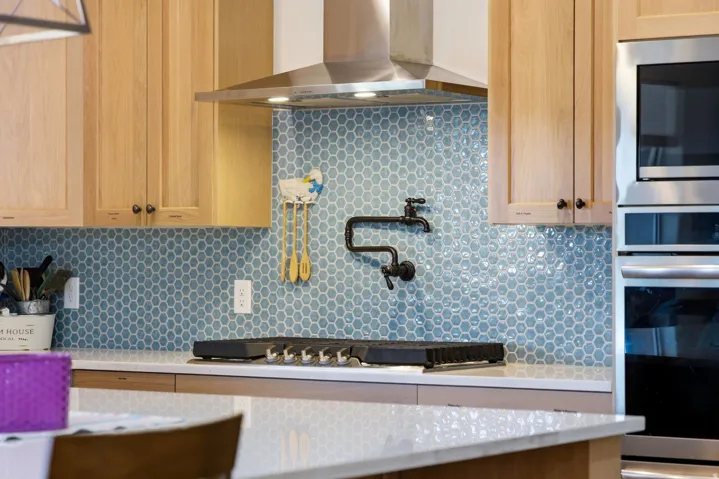 Kitchen featuring stainless steel appliances, tasteful backsplash, and light stone counters