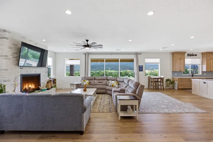 Living area featuring light wood-type flooring, a fireplace, ceiling fan, and recessed lighting