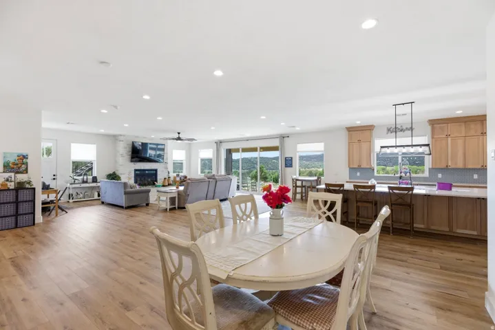 Dining space featuring light wood-type flooring, a large fireplace, a ceiling fan, and recessed lighting