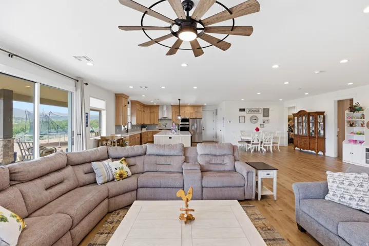 Living room with light wood-type flooring, a ceiling fan, and recessed lighting