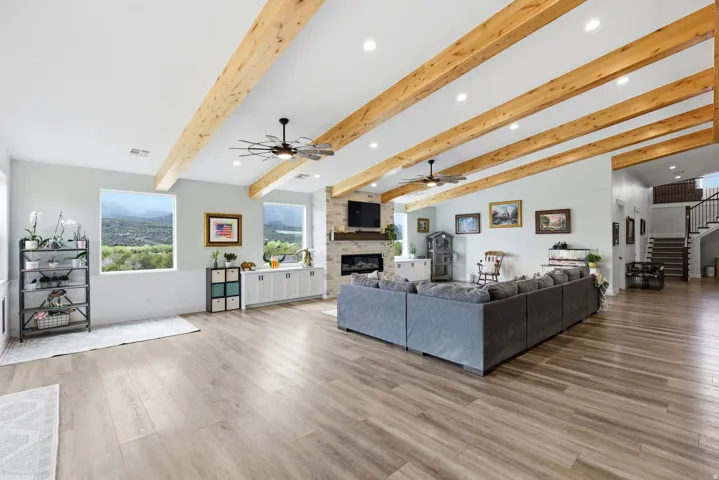 Living area featuring recessed lighting, ceiling fan, beamed ceiling, light wood finished floors, and a stone fireplace