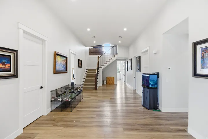 Hall with light wood-style floors, a high ceiling, and recessed lighting