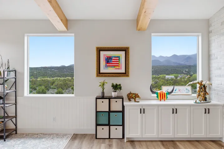 Detailed view of a wainscoted wall, wood finished floors, and beam ceiling