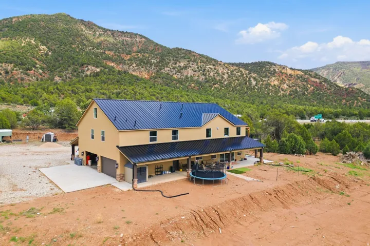 Rear view of property featuring a trampoline, a mountain view, a metal roof, a garage, and stucco siding