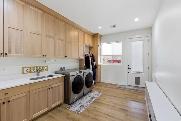 Laundry area featuring light wood-type flooring, washer and clothes dryer, cabinet space, and recessed lighting