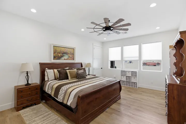 Bedroom with light wood-style floors, a ceiling fan, and recessed lighting